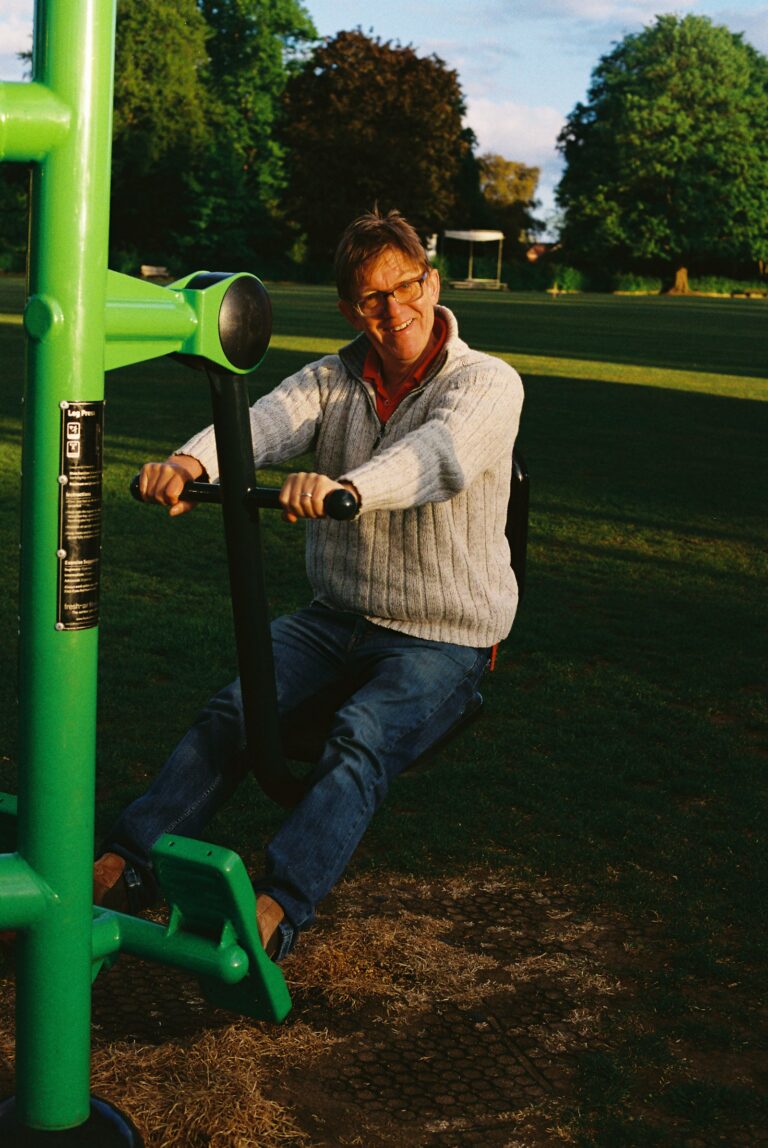 Senior man using outdoor gym strength-training equipment